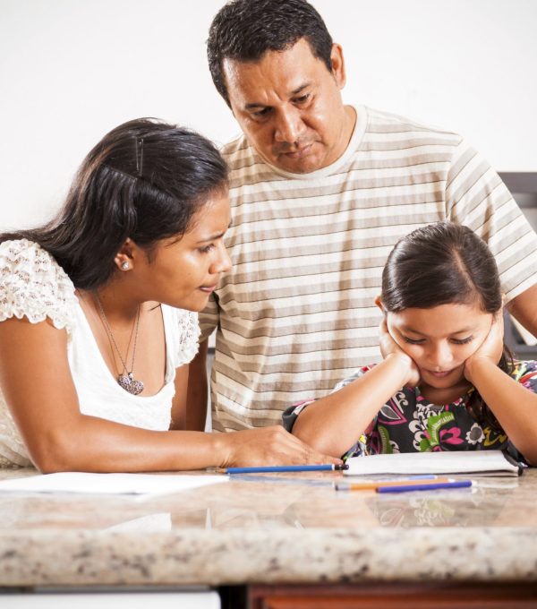 A photograph of parents helping their daughter who is struggling with her homework.